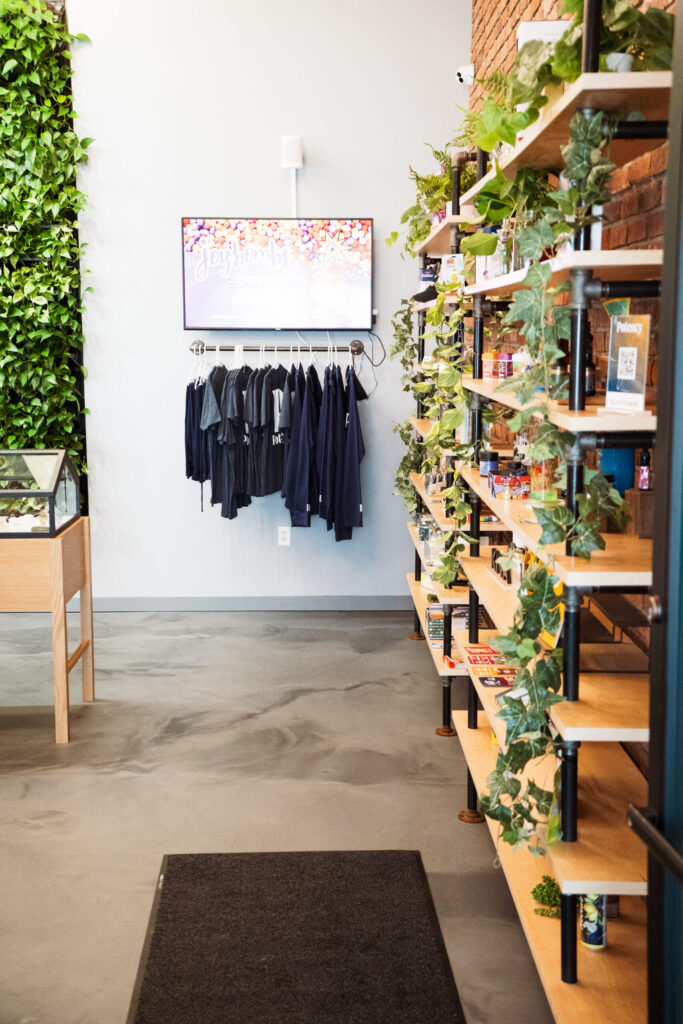 Merchandise display inside Potency dispensary featuring apparel and cannabis products on wood shelves.

